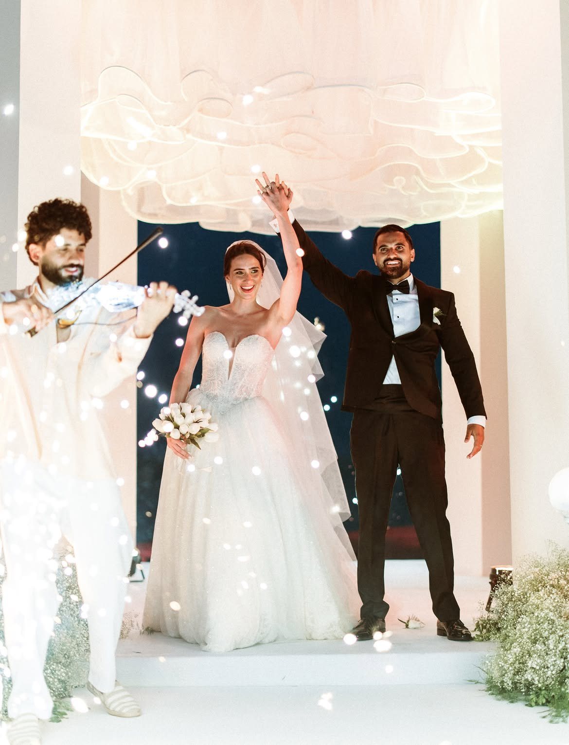 Newlyweds on stage with a violinist and sparklers