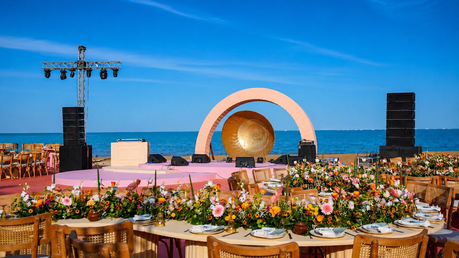 Riah beach wedding set-up with floral tables and a stage facing the sea